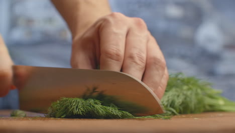 Closeup-of-cutting-green-dill-on-a-board-in-the-kitchen-on-a-wooden-board.-cutting-grass-and-greenery